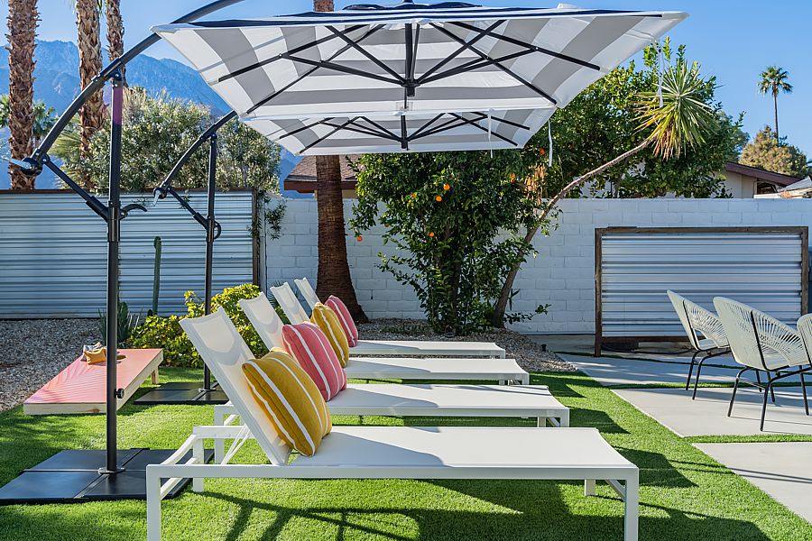 Backyard outdoor chaise lounge chairs with cantilever umbrellas and colorful pillows.